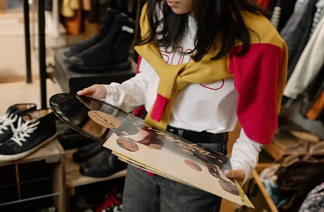 A woman holding a record album, enjoying a vintage shopping spree for Valentine's Day, seeking extraordinary and unique items for each other.