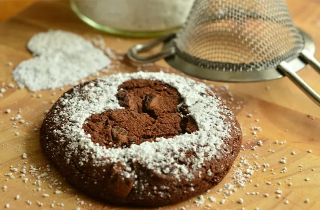 A chocolate cookie with a dusting of powdered sugar on its surface.