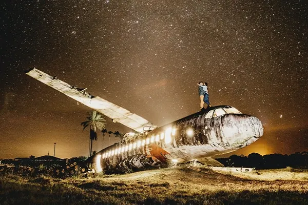A couple standing on top of an airplane under a starry night sky, creating a romantic and unforgettable Valentine's Day camping experience.