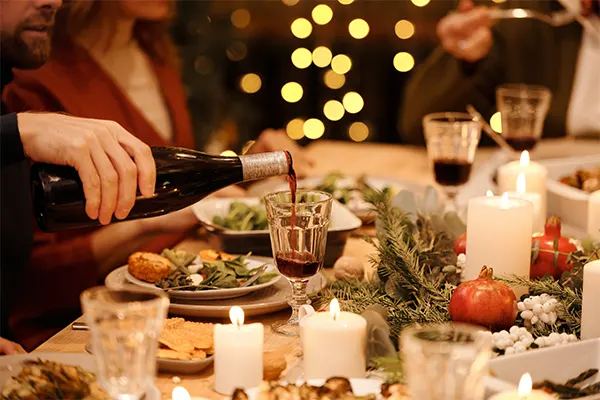 A man gracefully pours wine into a glass at a beautifully set dinner table, creating an intimate and romantic atmosphere.