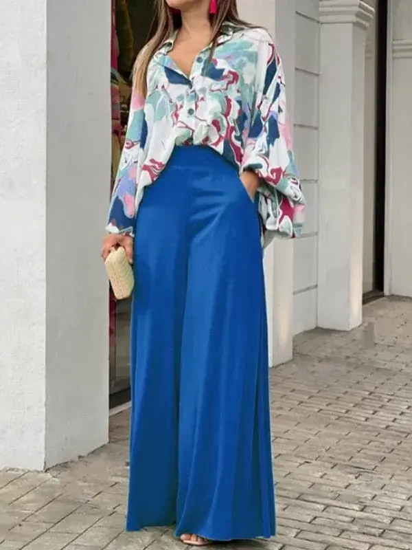 A woman wearing blue palazzo pants and a floral blouse.