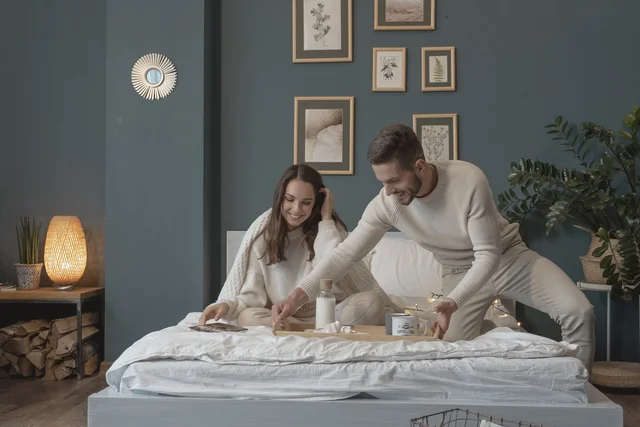 A couple enjoying a romantic Valentine's Day breakfast in bed, sipping hot coffee and taking a break from their usual morning routine.