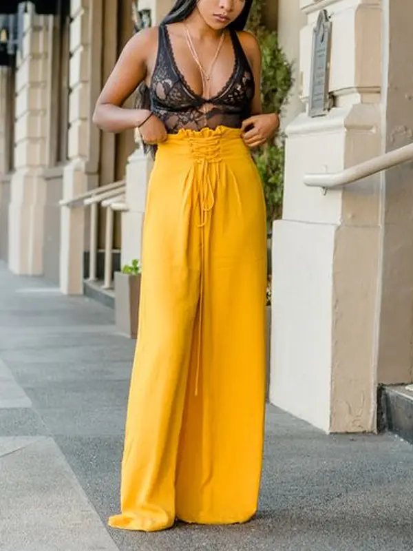 A woman wearing yellow palazzo pants and a lace top at a wedding.