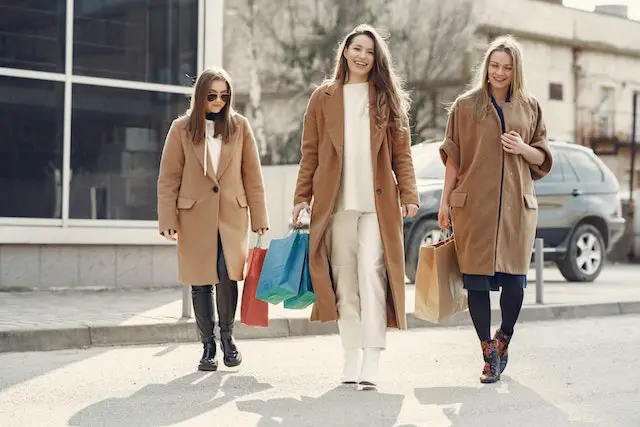 happy women walking with paper bags after shopping