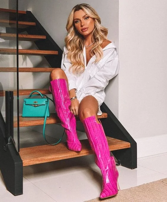 A blonde woman in pink boots sitting on stairs.
