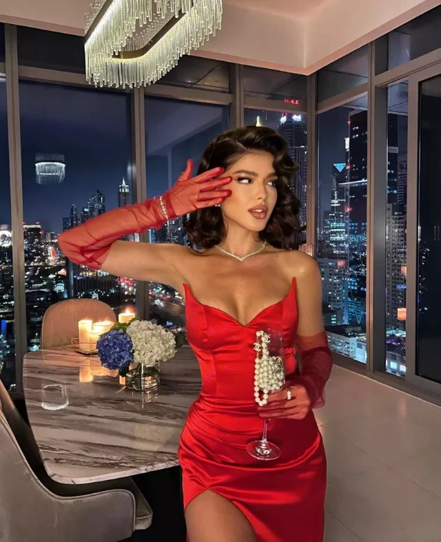 A woman in a red Valentine's Day baddie outfit, showcasing her style and grace in front of a window.