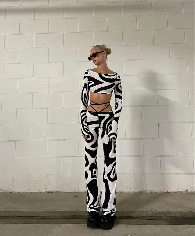 Confident woman in black and white striped pants and a crop top, embracing bold prints fashion trend.