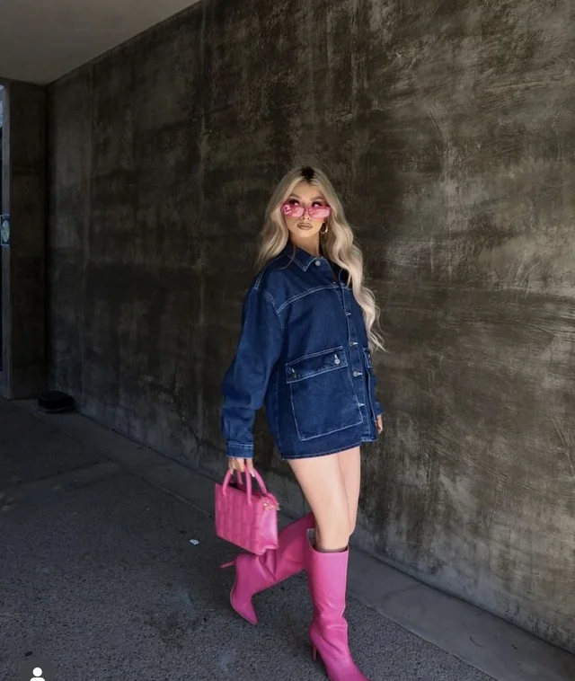 A woman wearing a denim jacket and pink boots.