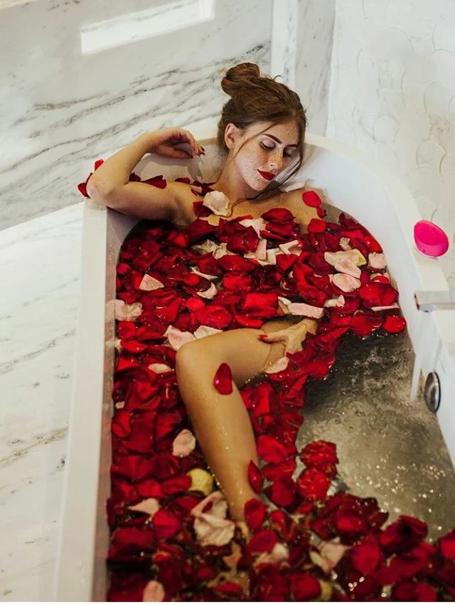 A woman luxuriating in a bathtub filled with fragrant rose petals, creating a serene and indulgent atmosphere.