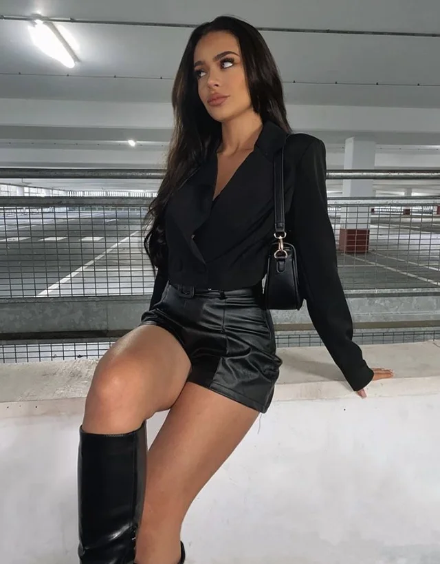 A woman wearing black leather shorts and boots.