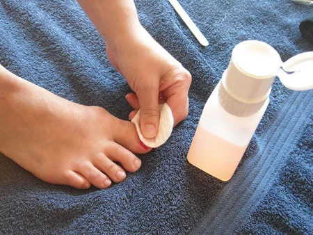 Woman removing nail polish during pedicure.