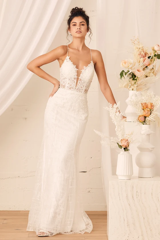 A bride wears a sleeveless white lace wedding gown with a plunging V-neckline