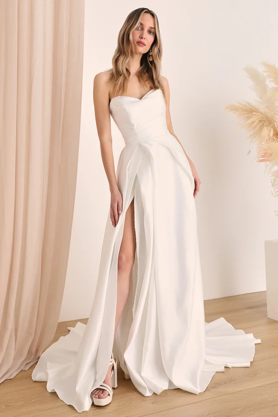 a woman wearing an elegant white strapless wedding gown with a thigh-high slit