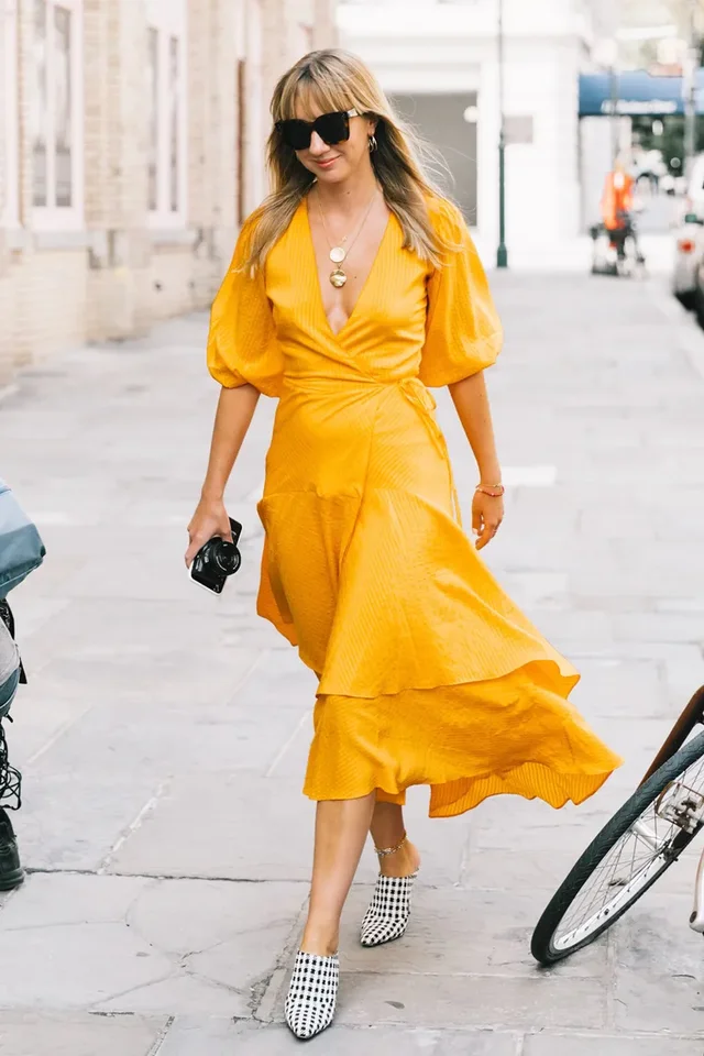 a woman in a yellow dress walking on a sidewalk