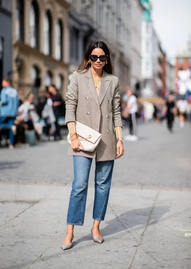 a woman in sunglasses and a blazer paired up with jeans