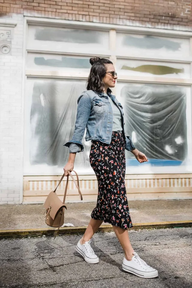 a woman walking down the street in denim jacket and midi skirt