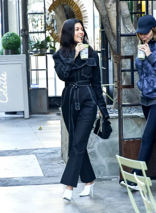 a woman in a black jumpsuit holding a cup of coffee