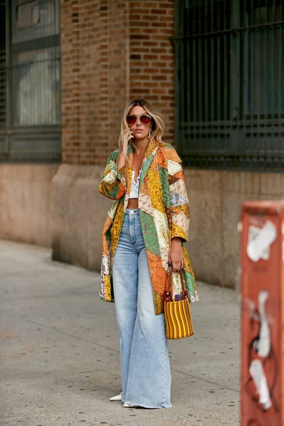 a woman in a patchwork jacket with flared jeans