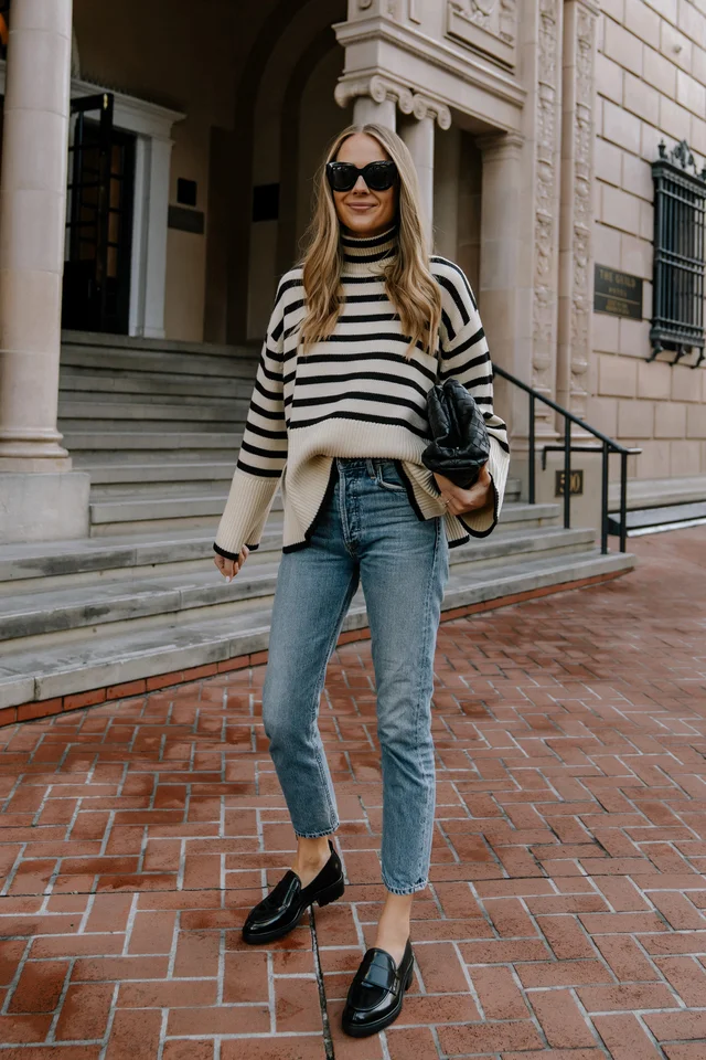 a woman wearing a Toteme Striped Sweater and Jeans